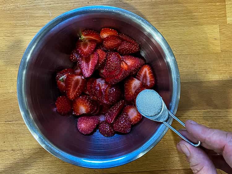 Adding sugar to sliced strawberries
