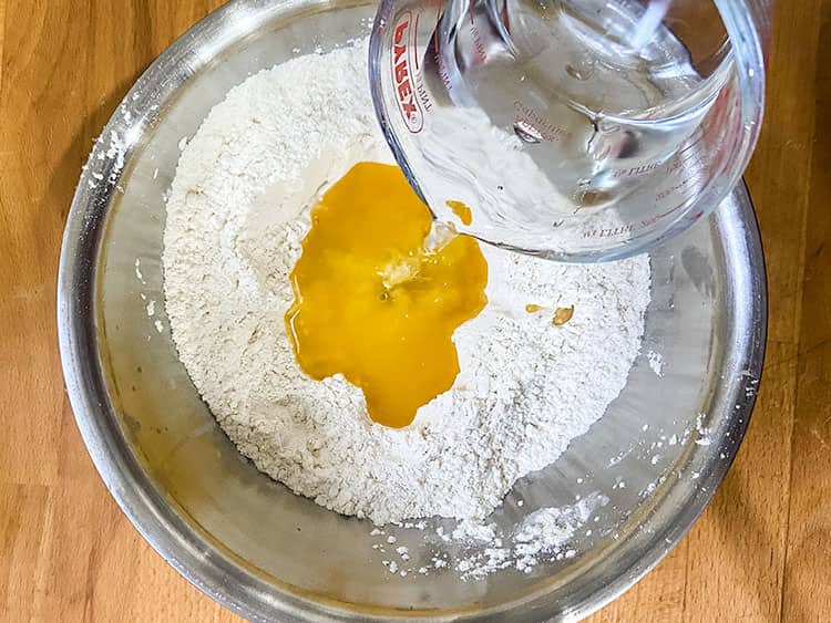 adding wtaer to flour and butter in a bowl.