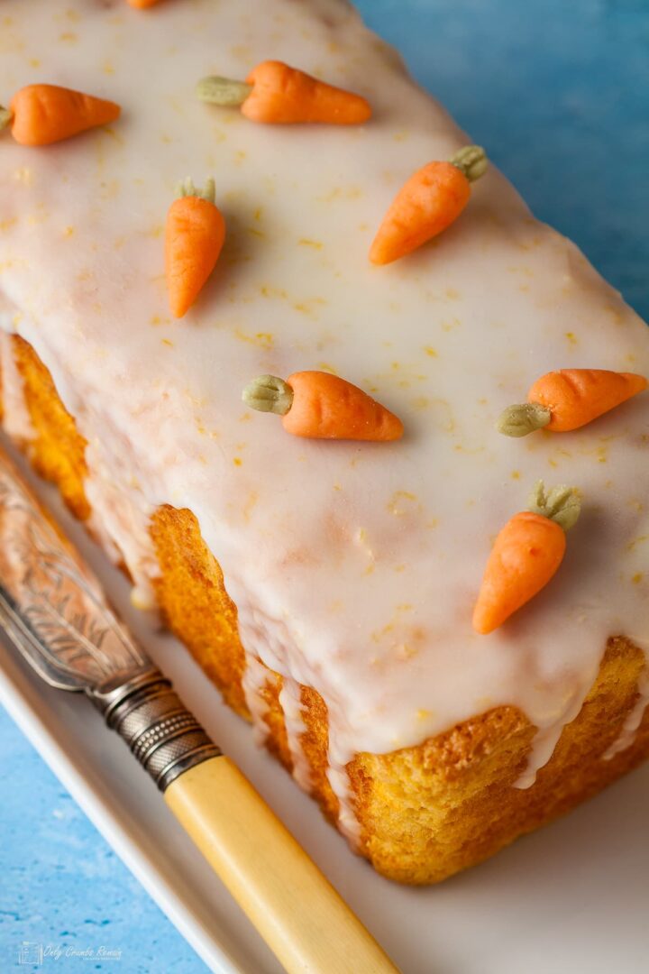 swiss carrot loaf cake on plate with cake knife by side.