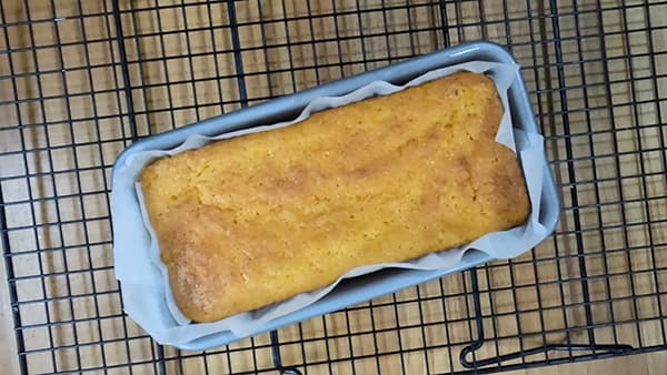 cooked cake in tin on cooling rack.