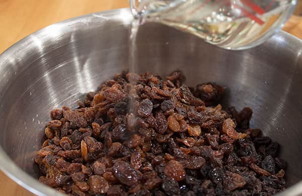 pouring sherry over dried fruit in a bowl.