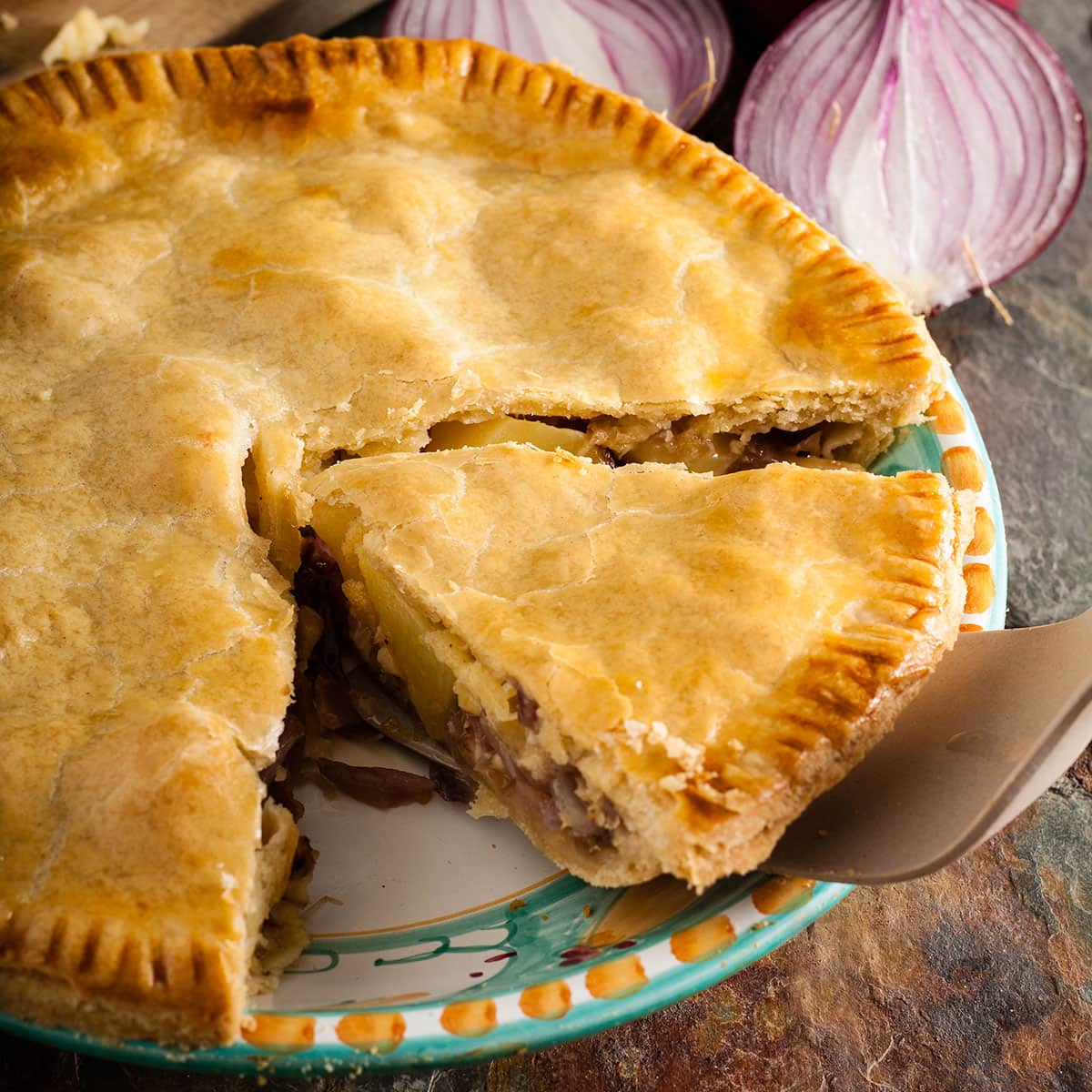 Lancashire cheese and onion plate pie with slice cut.
