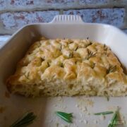 half a rosemary and garlic focaccia in a baking dish cut to show texture.