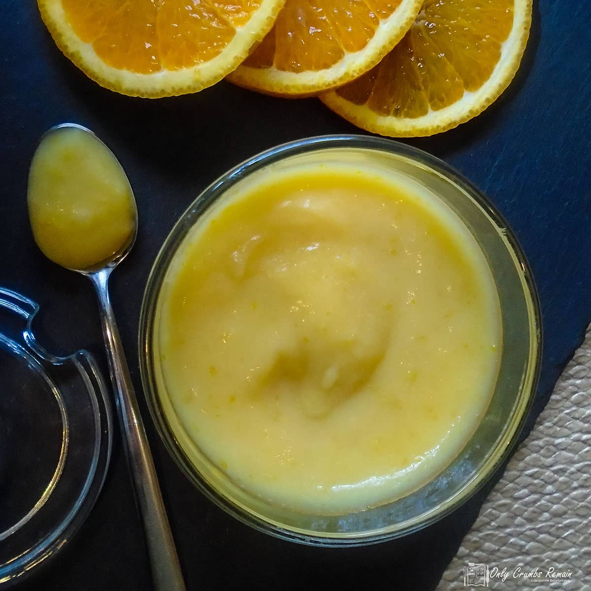 jar of homemade orange curd with a spoon by the side.