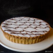 whole bakewell tart on a white serving plate.