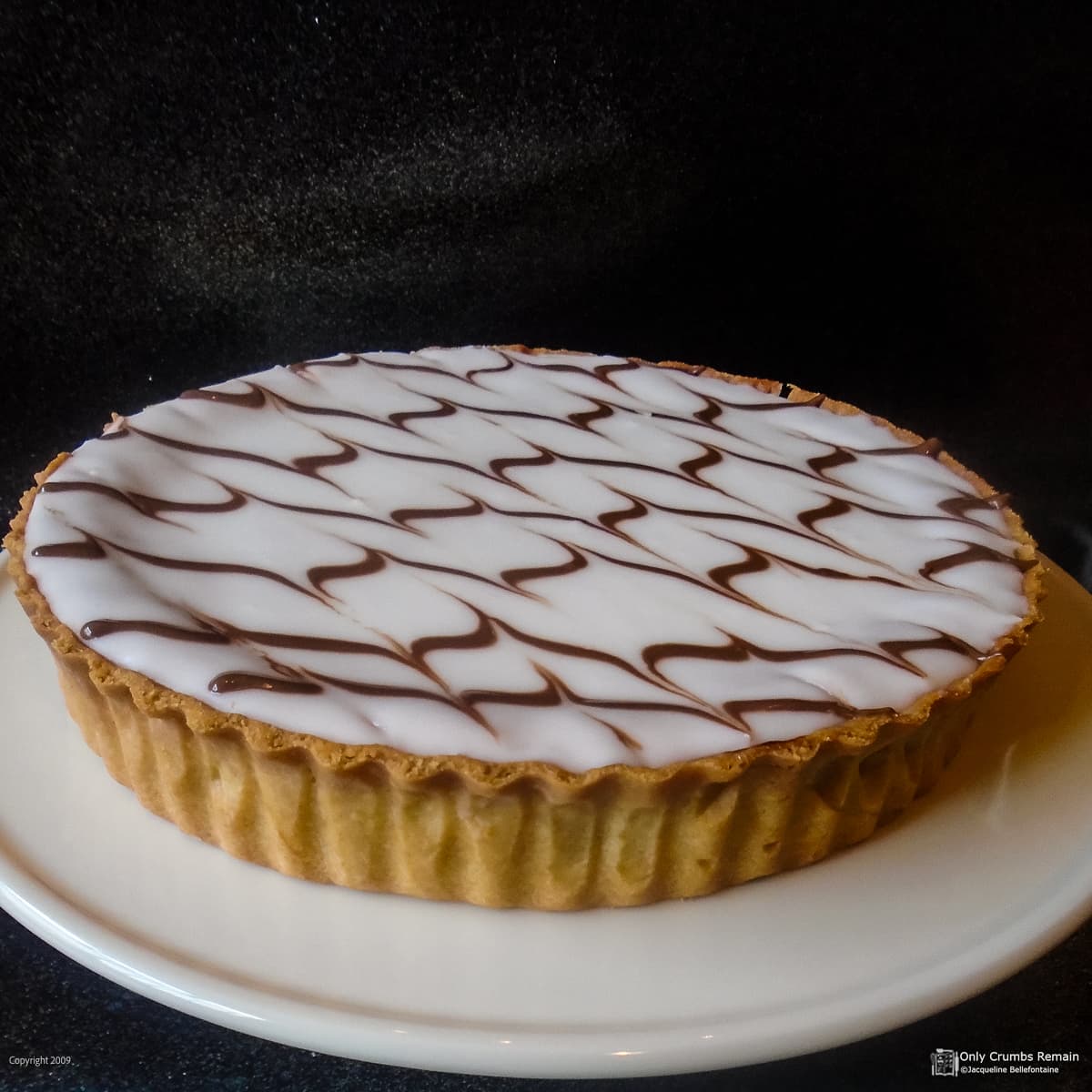 whole bakewell tart on a white serving plate.