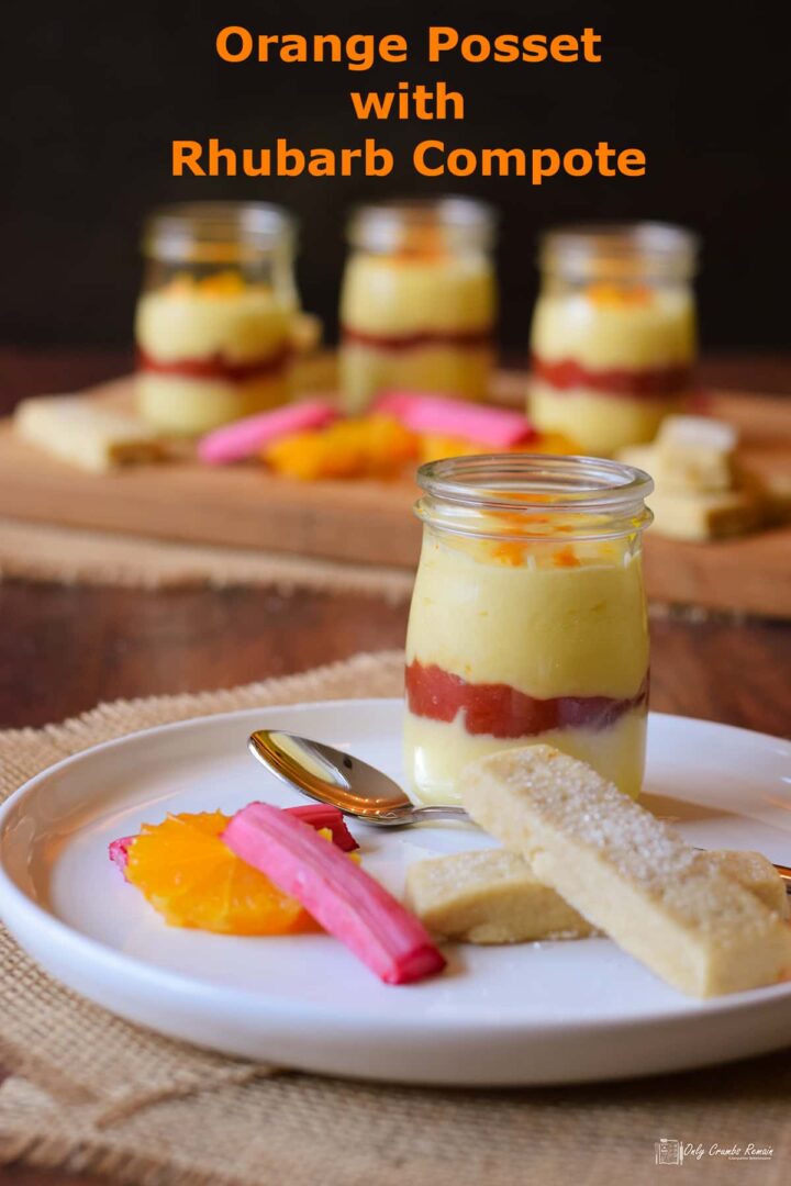 orange posset layered with rhubarb compote in glass jar. served with shortbread orange slices and rhubarb batons.