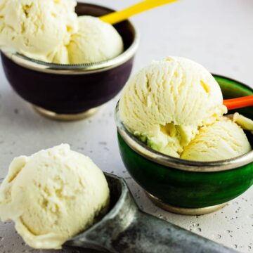 two bowls and an ice cream scoop filled with basil ice cream.