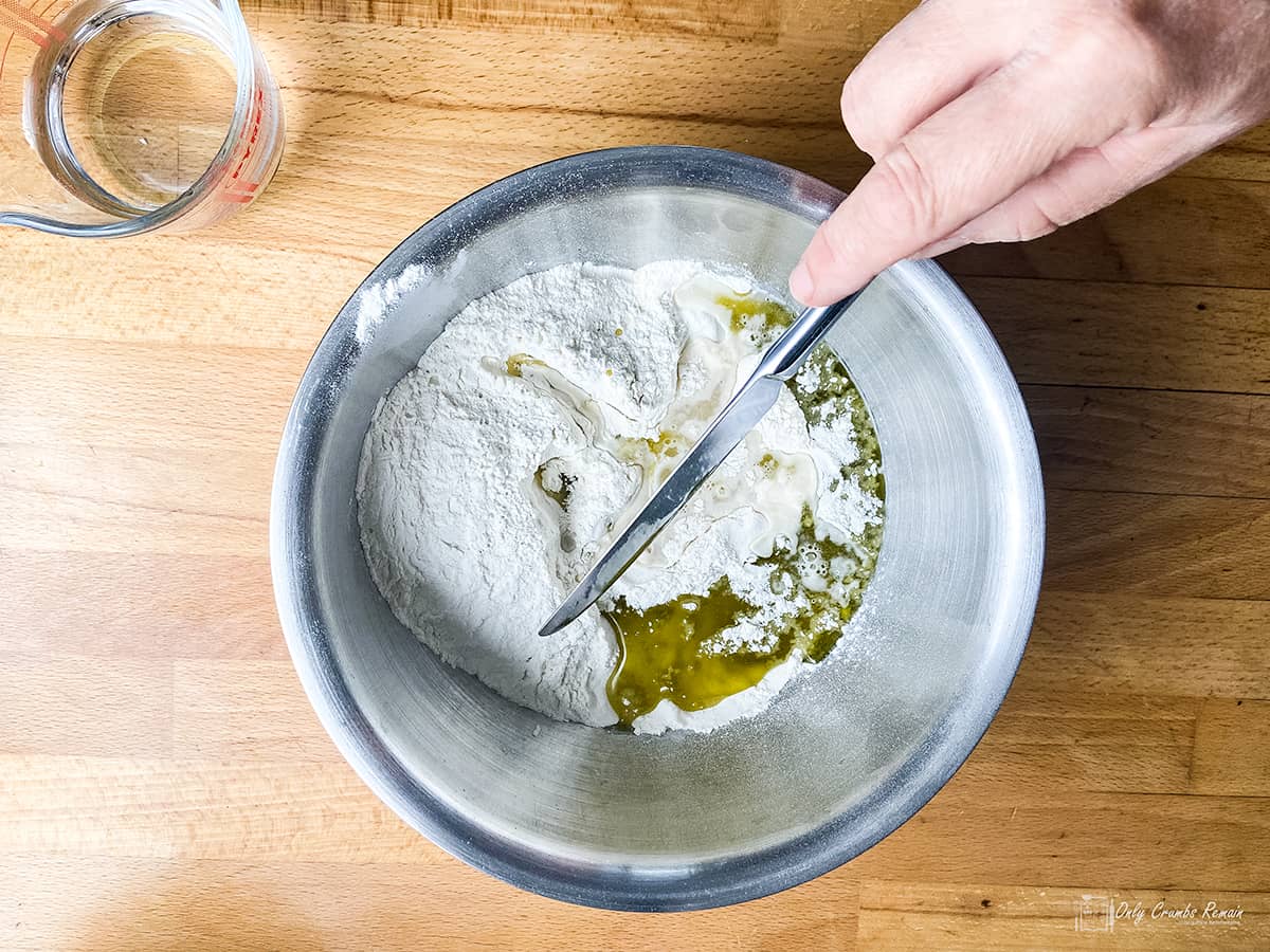 flour and oil in a mixing bowl. Hand hloding knife ready to mix ingredients.