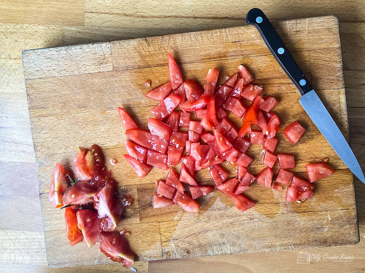 Seeded and diced tomatoes on a chopping board with a knife.