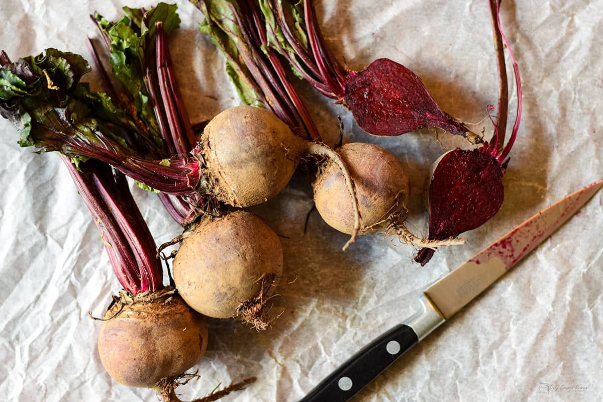 beetroot complete with stems and some leaves.  One cut in half with knife.
