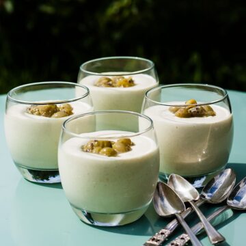 4 glasses of gooseberry fool topped with gooseberries.