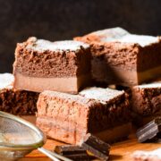Chocolate orange magic cake cut into squares and stacked on a wooden board.