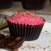 Chocolate and beetroot cupcake on white plate with chunks of chocolate and choco,ate shavings