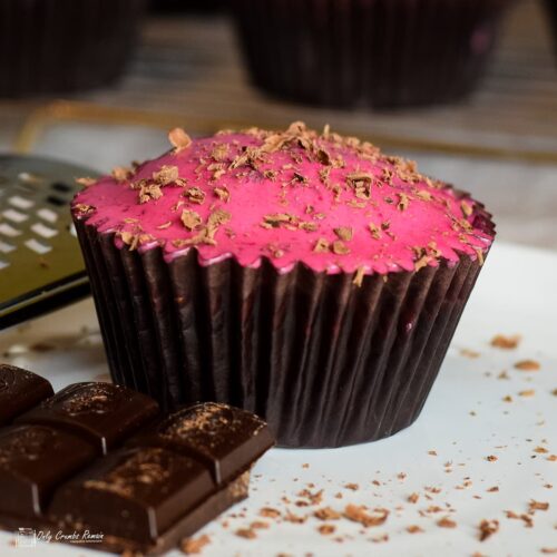 Chocolate and beetroot cupcake on white plate with chunks of chocolate and choco,ate shavings