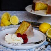 slice of lemondrizzle olive oil cake on a plate with creme fraiche and raspberries