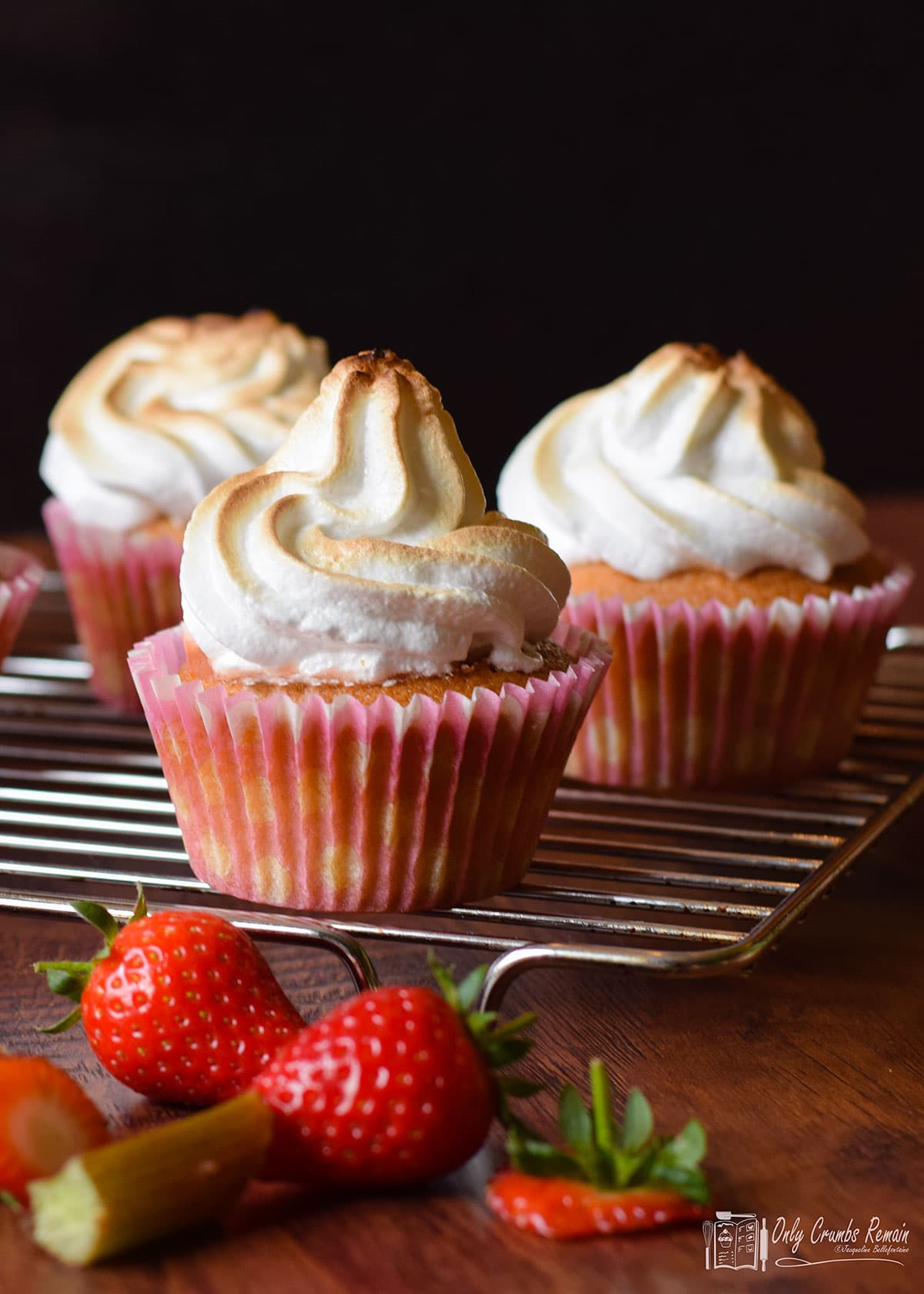 rhubarb and strawberry meringue cupcakes on a baking rack