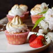 Rhubarb and strawberry meringue cupcake on a plate with fresh strawberries on the side
