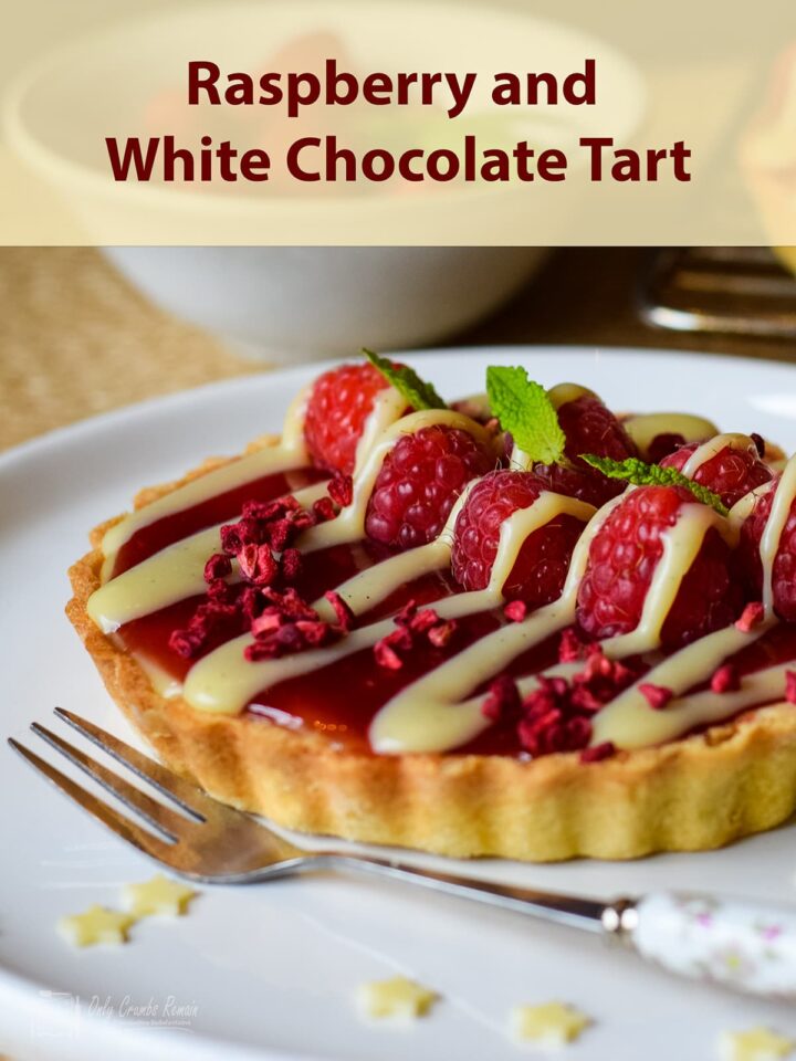 single raspberry and white chocolate tart on serving plate.