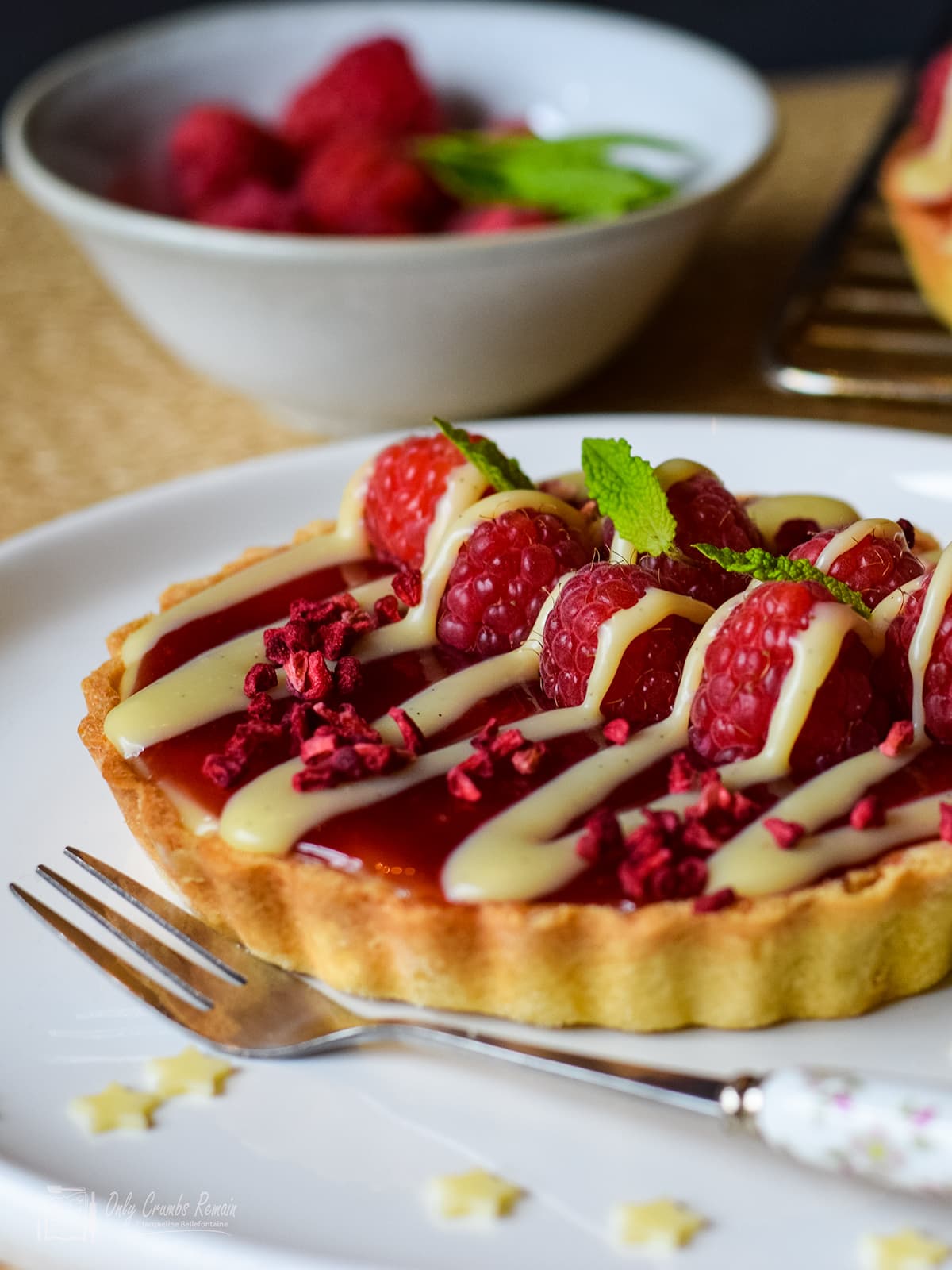 raspberry and white chocolate tart on serving plate with dessert fork.