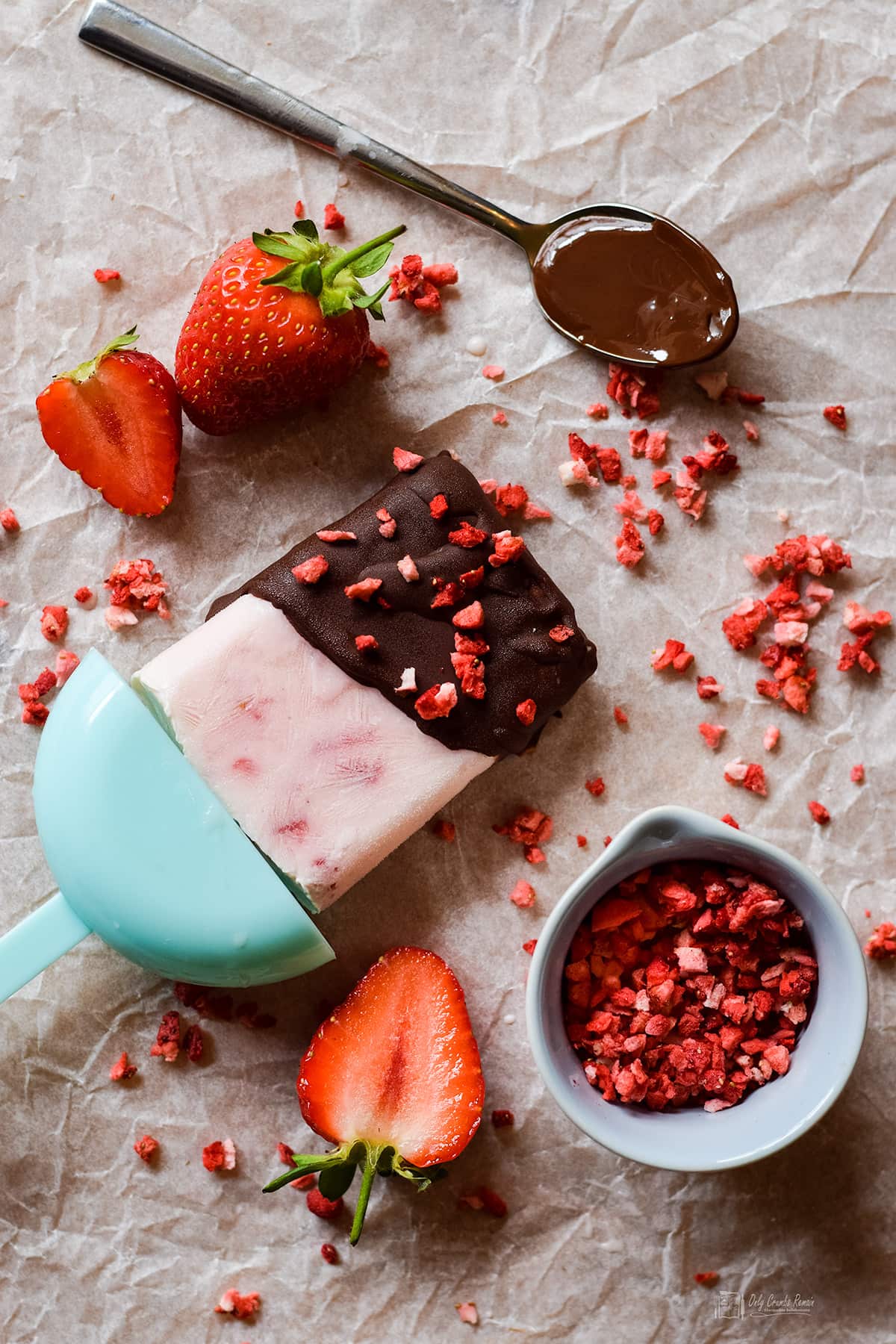 strawberry greek yogurt lolly coated in chcolate with strawberries and freeze dried strawberries around it