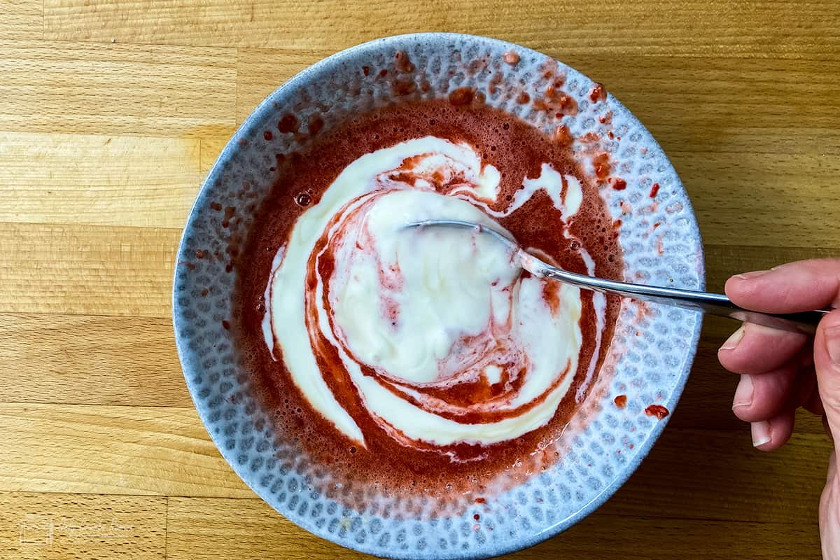 combining yogurt and strawberry puree in bowl.