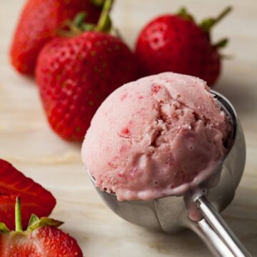 scoop of homemade fresh strawberry ice cream surrounded by strawberries.