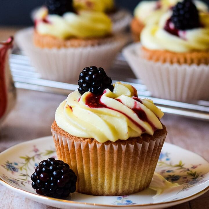 blackberry and pear cupcake on plate with more behind.