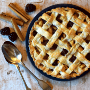 blackberry and pear tart in tin with spoons and fruit around.