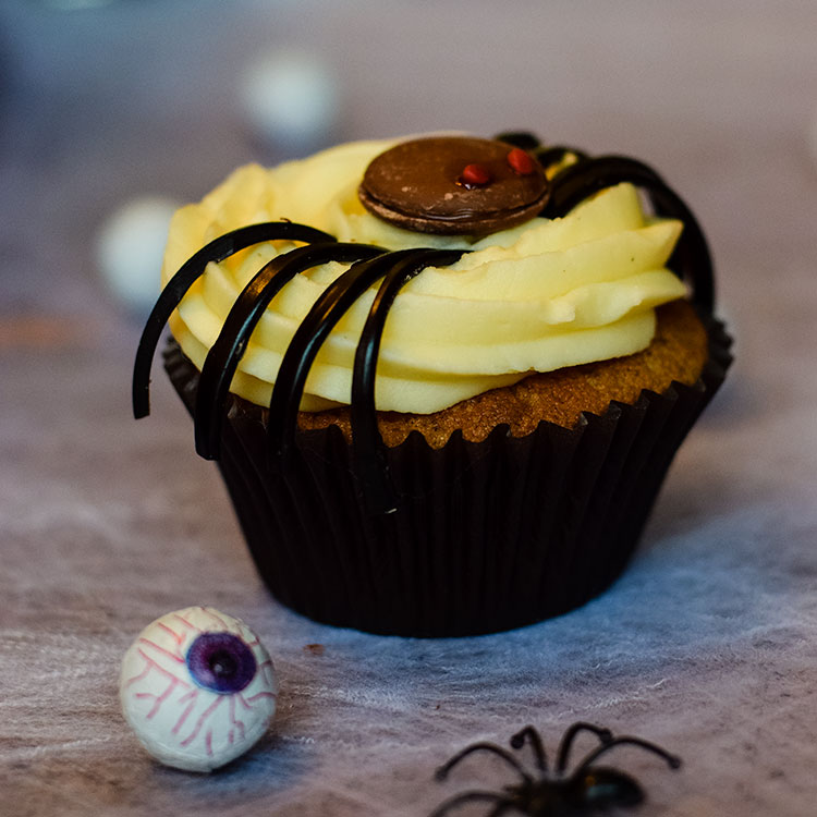 a blackcurrant and liquorice spider cupcakes with fake eyeball in front.