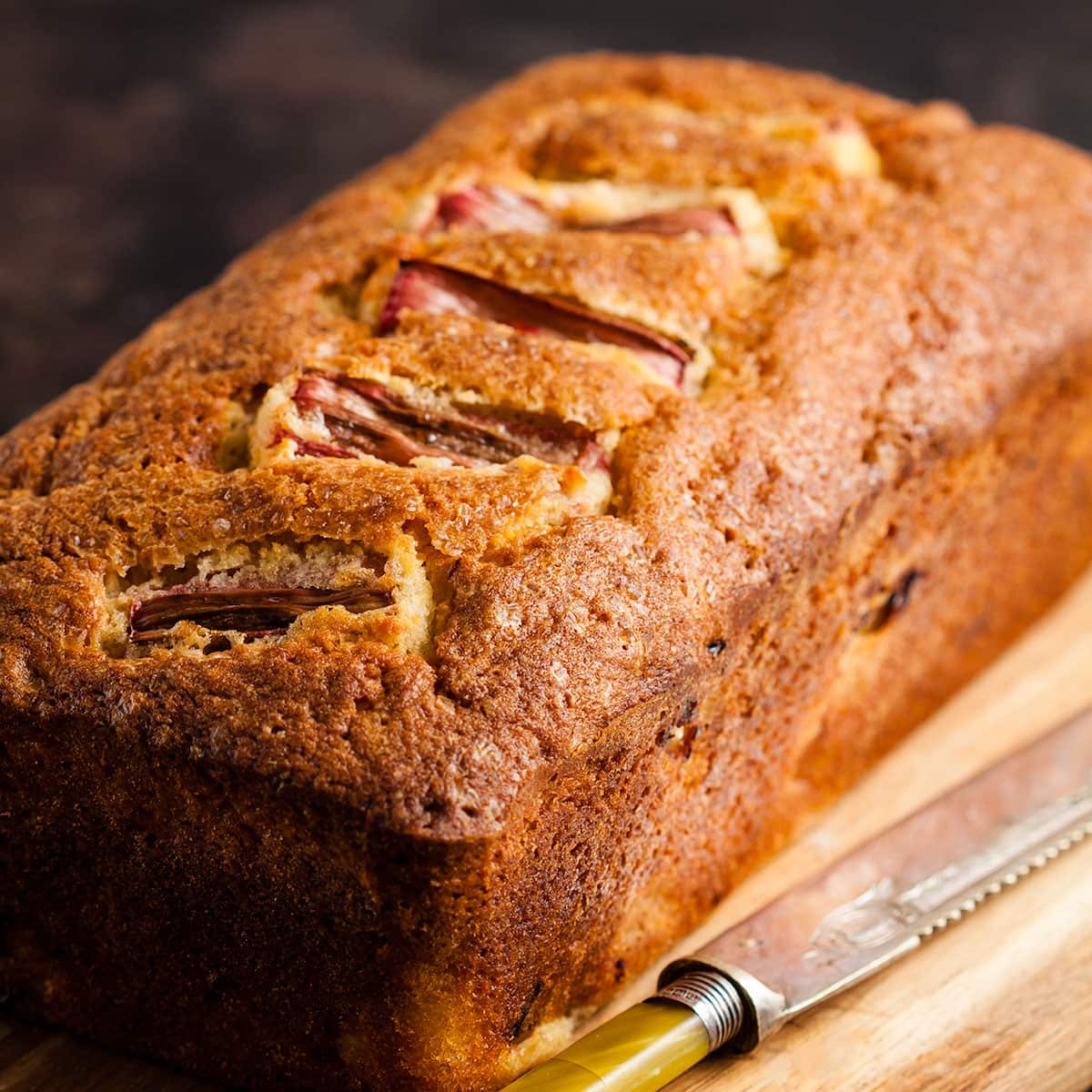 rhubarb and ginger loaf cake on a wooden board.