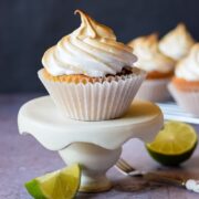 lime meringue cupcake on stand with more behind on cooing rack