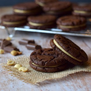 two chocolate peanut butter cookies in front with remainder on a cooling rack behind