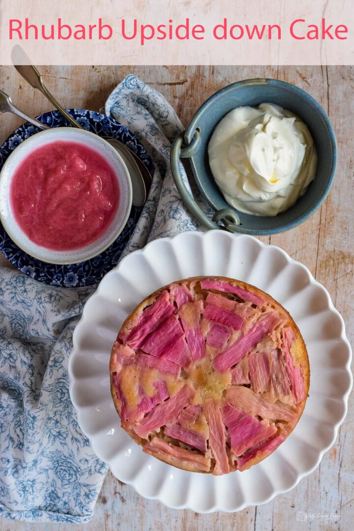 rhubarb upside down cake on a plate with bowls of stewed rhubarb and cream above.