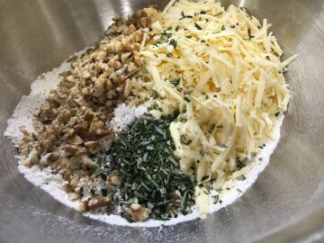 adding cheese, walnuts and rosemary in a bowl with the sifted flour.