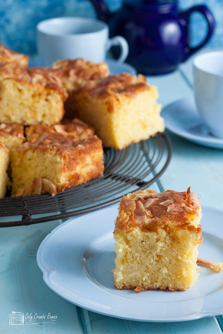 piece of pineapple and coconut traybake on a plate with more on wire plate behind