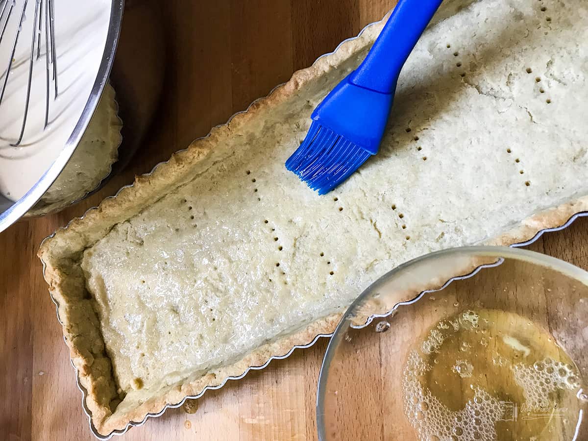 Brushing pastry case with egg white to seal.