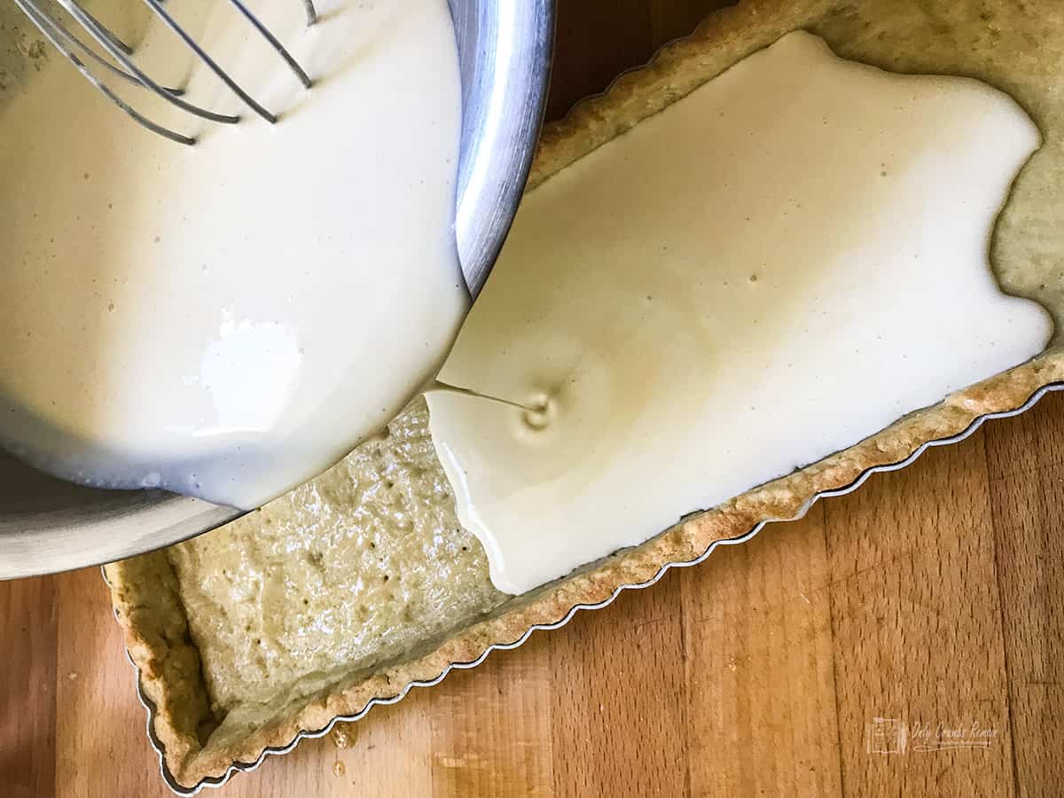 pouring filling into pastry case.