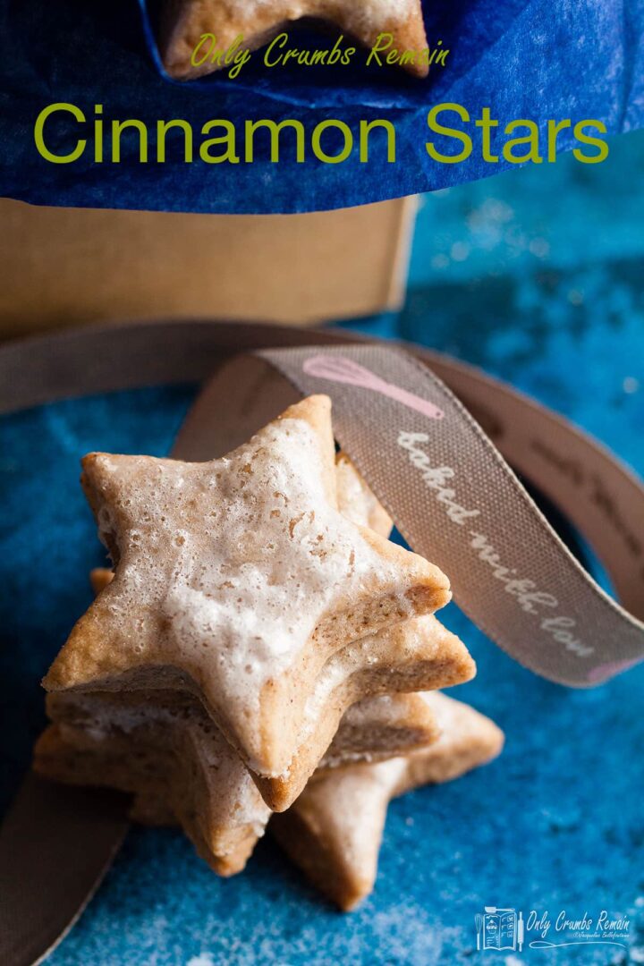 cinnamon star cookies stacked in front of box.