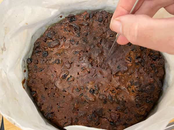 Testing the cake is cooked with a skewer.
