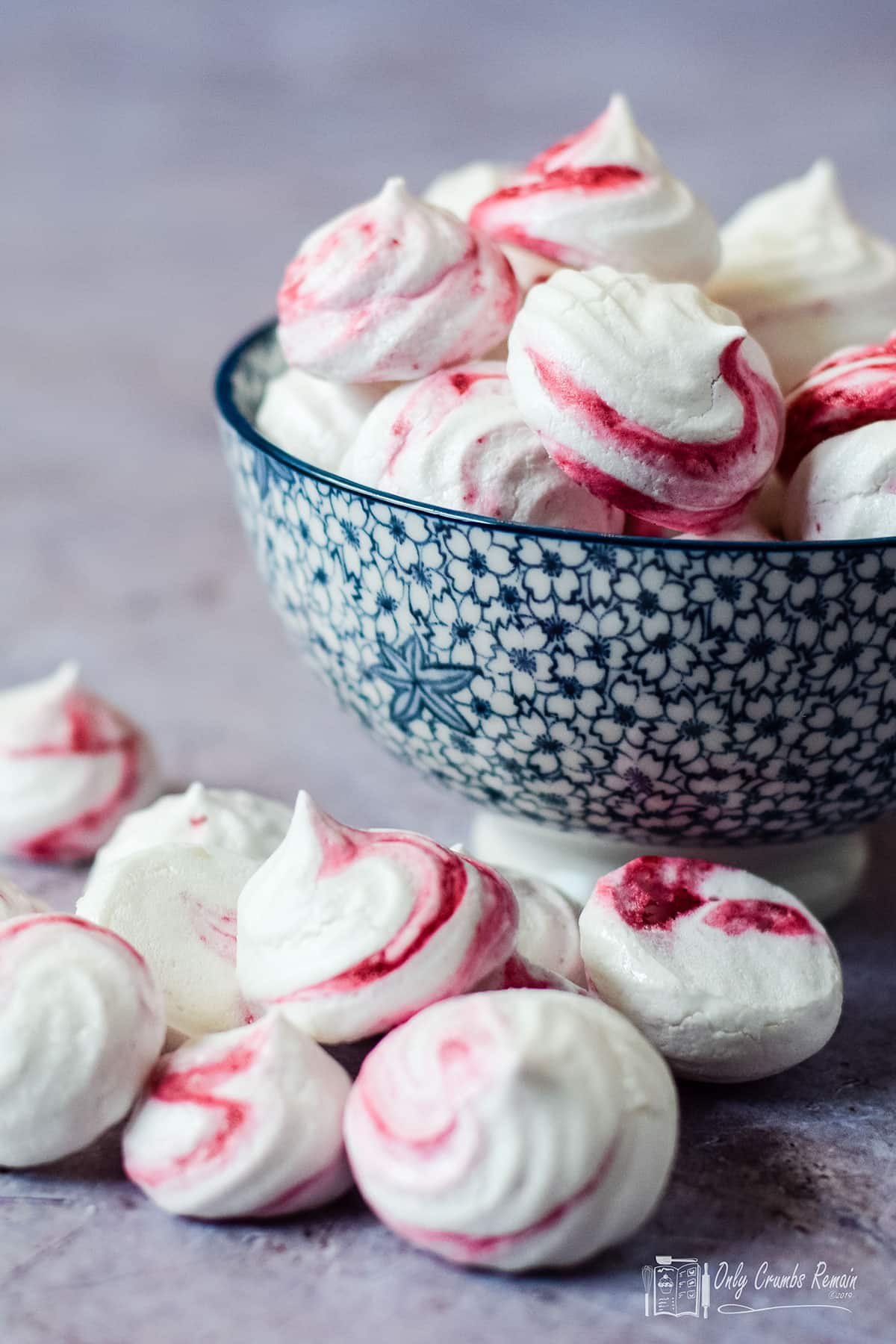bowl of vegan meringue kisses with some on the table.