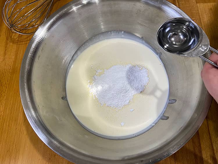unwhipped cream in bowl with icing sugar and adding kirsch.