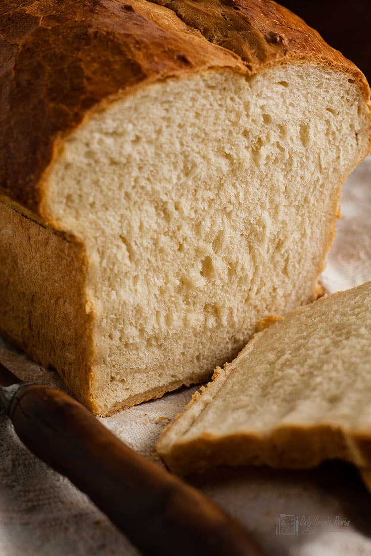 Crusty white tin loaf with slice laying down.