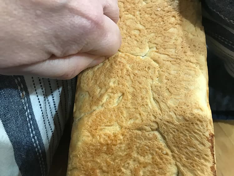 tapping loaf on bottom to check if it is cooked.