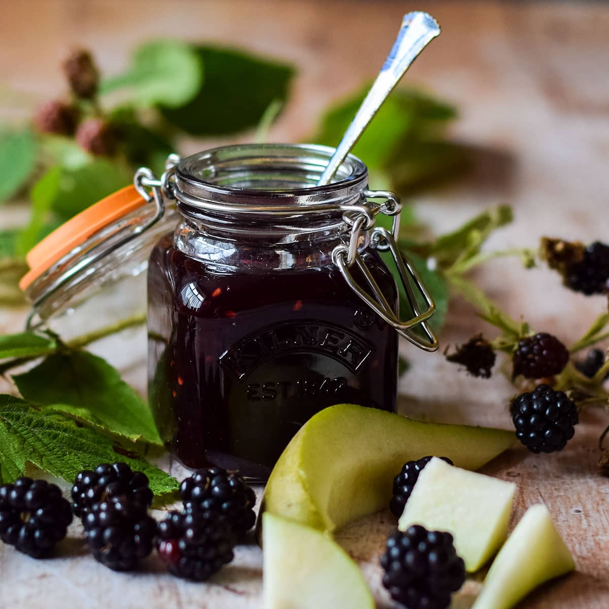 jar of blackberry and pear jam with fruit around it.