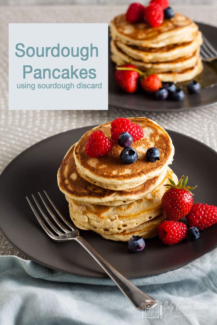 sourdough pancakes stacked on grey plates and served with berries.