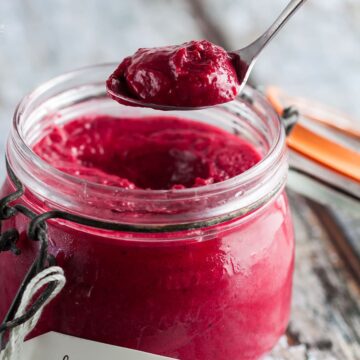 spoon of blackcurrant curd coming out of jar.