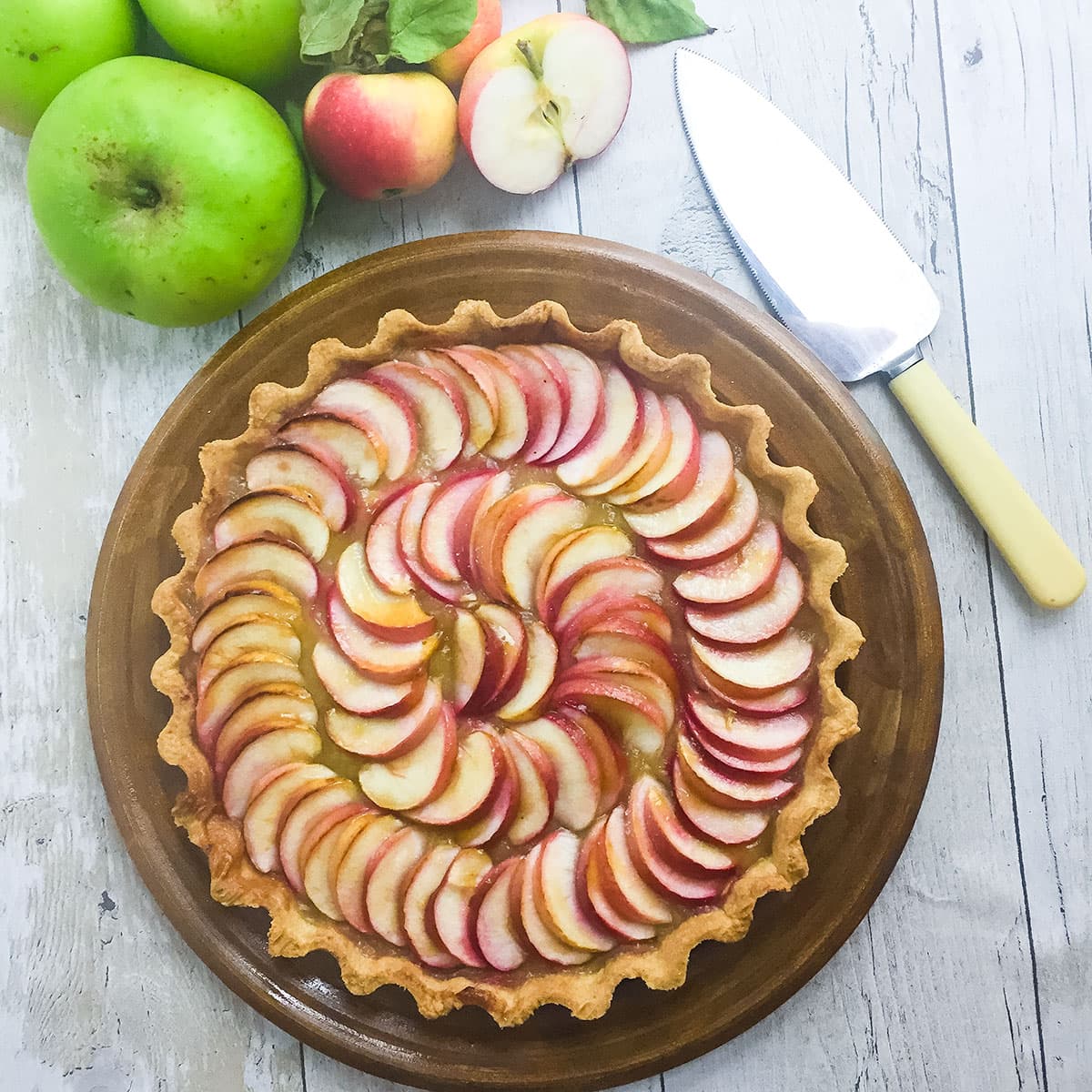 French apple tart with fresh apples and a cake slice on side.