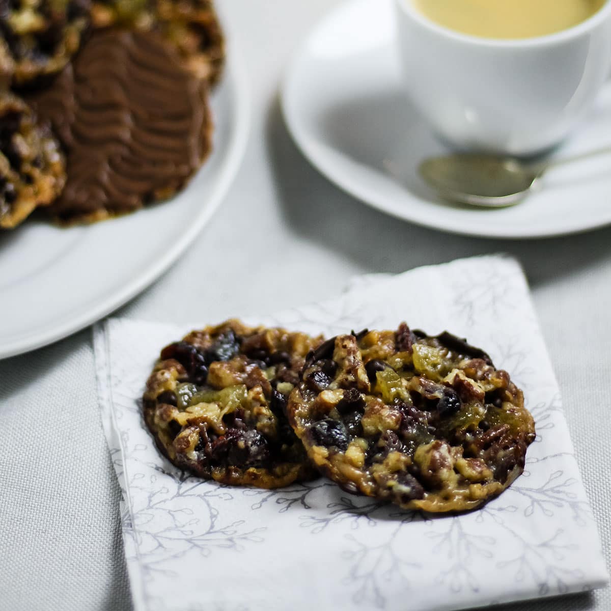 chocolate florentines on a napkin in front of a cup of coffee.