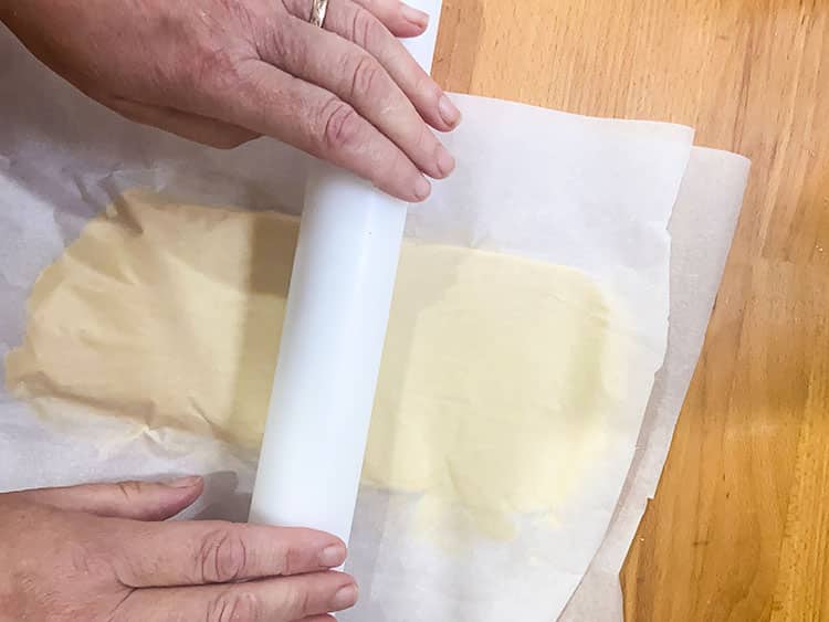 rolling out butter between two layers of parchment.